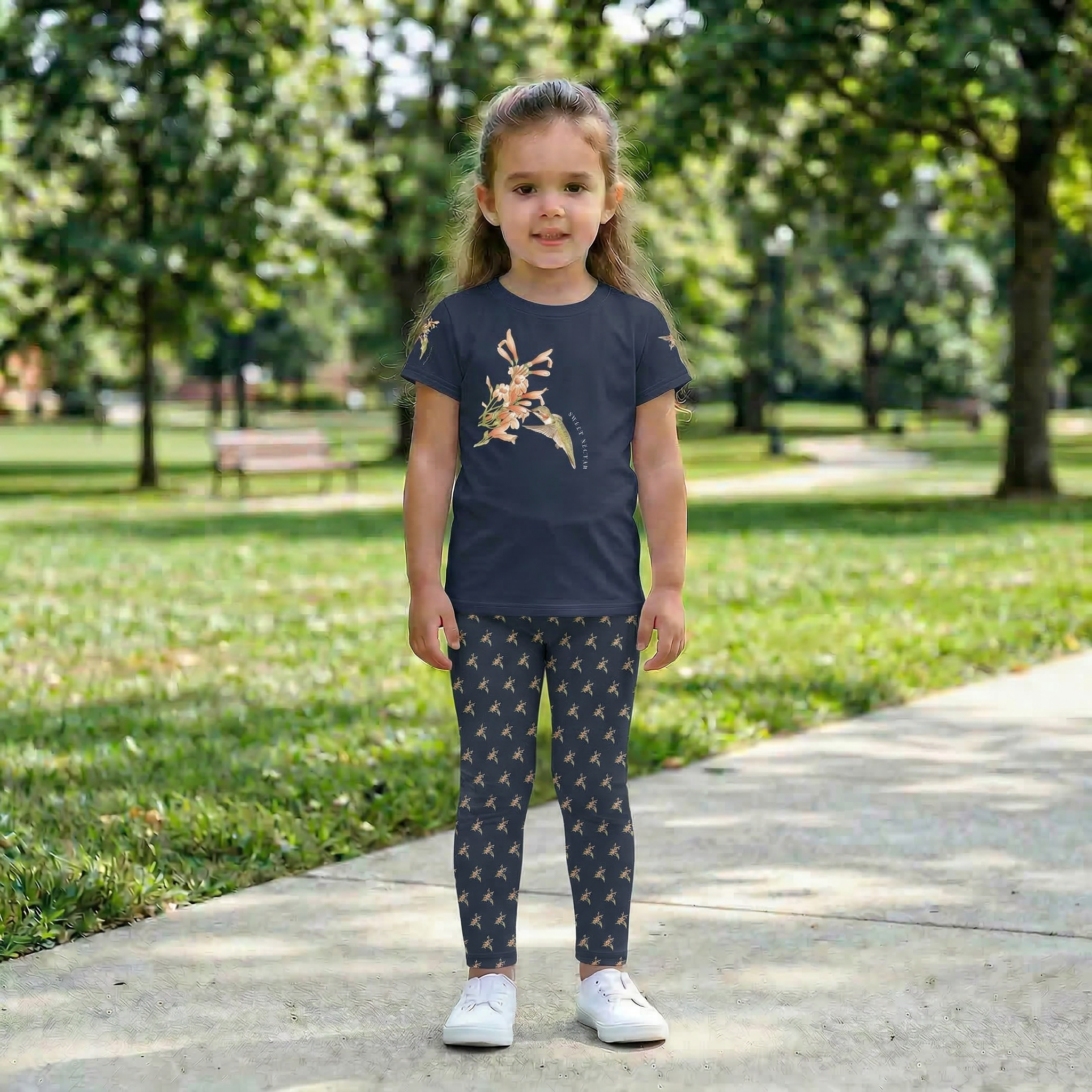 Close up of a child walking outdoors wearing Tinywing Tales Sweet Nectar hummingbird print leggings, along with matching Tee