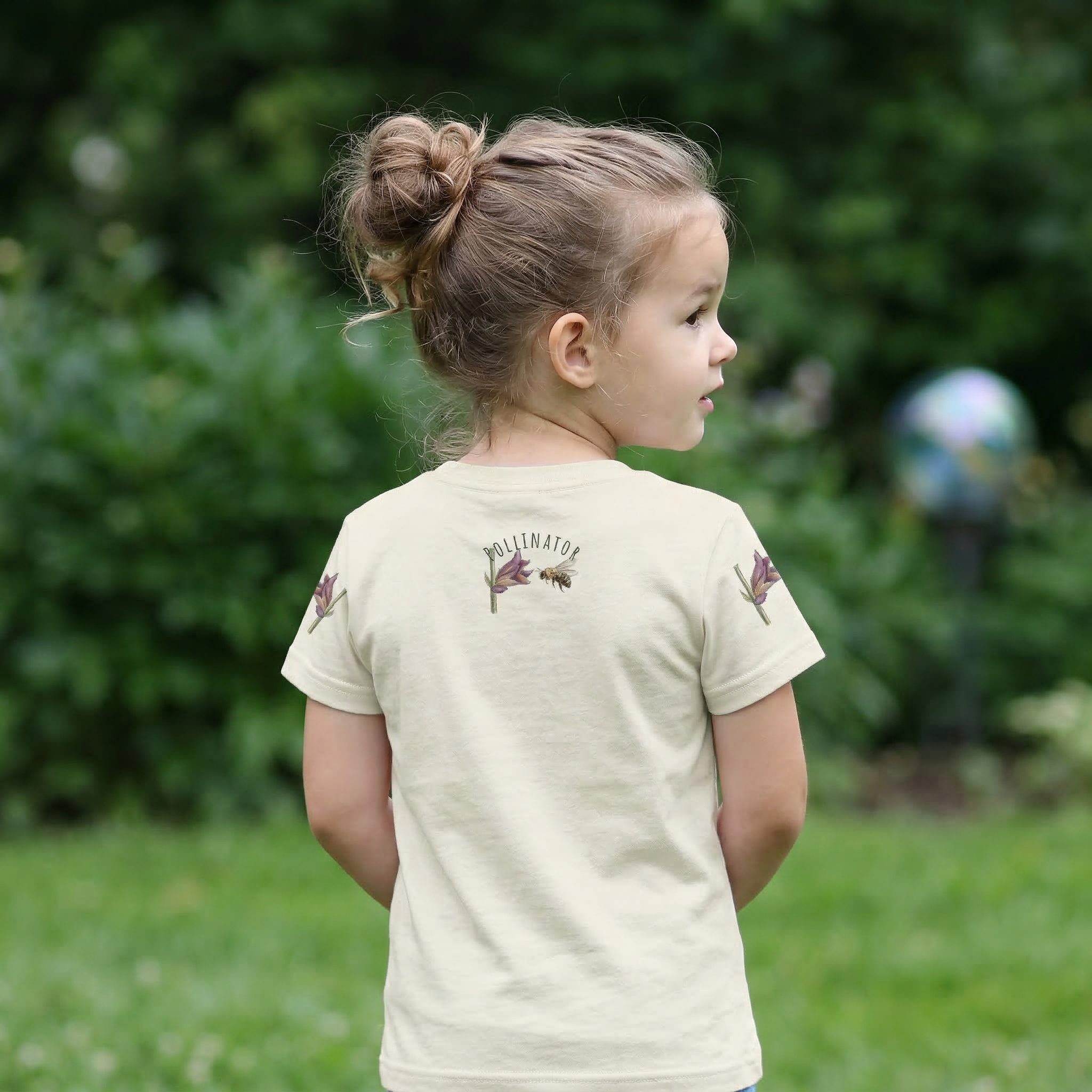 Backview of Toddler Girl  wearing cream Colored t-shirt with bee and flower design and text 'Small Bee, Big Job' Tinywing Tales Golden Dust Collection