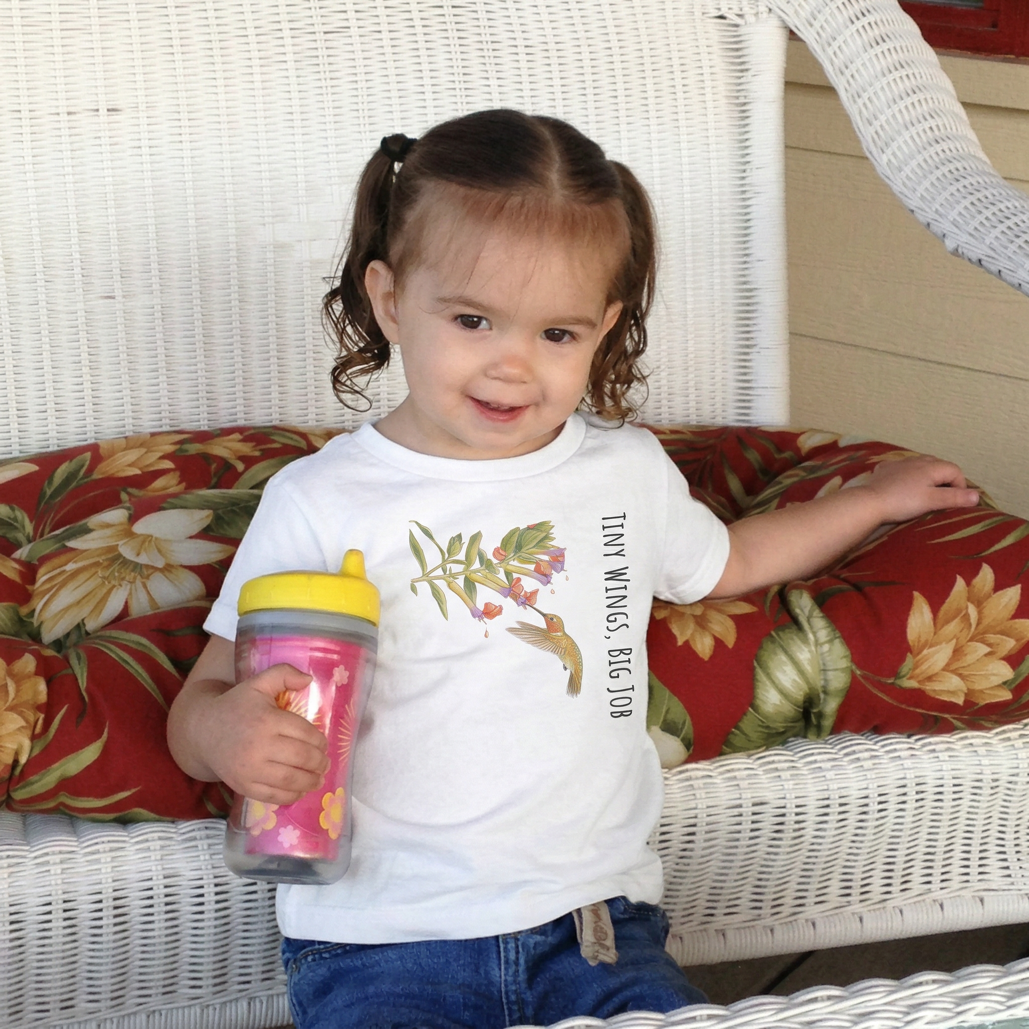 A toddler playing outdoors wearing the Tinywing Tales hummingbird t-shirt from The Nectar Quest collection.