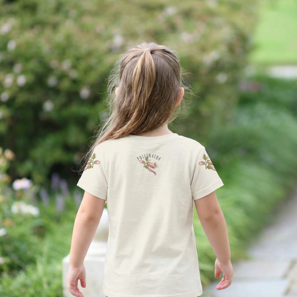 Back view of a Child wearing a cream t-shirt with floral designs in a garden setting