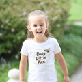 Child wearing a 'Busy Little Bee' t-shirt outdoors