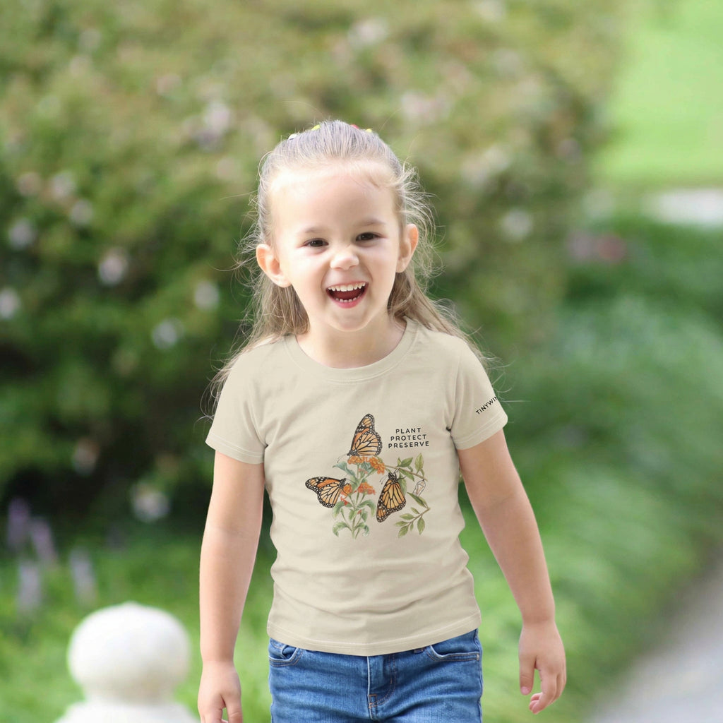 Toddler wearing a t-shirt with butterfly design outdoors. Tinywing Tales