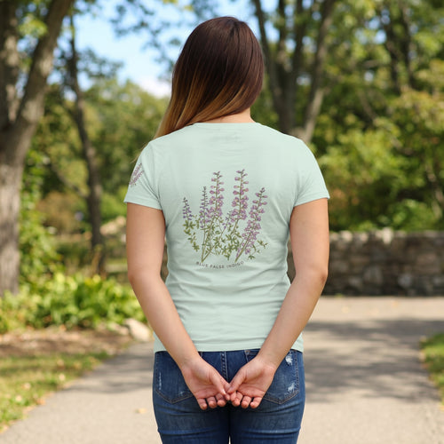 rear view  of Woman wearing a light sage t-shirt with "blue false indigo" flora design
