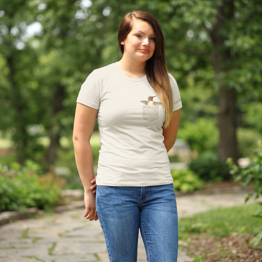 woman wearing a light colored t shirt with a faux pocket hummingbird design 