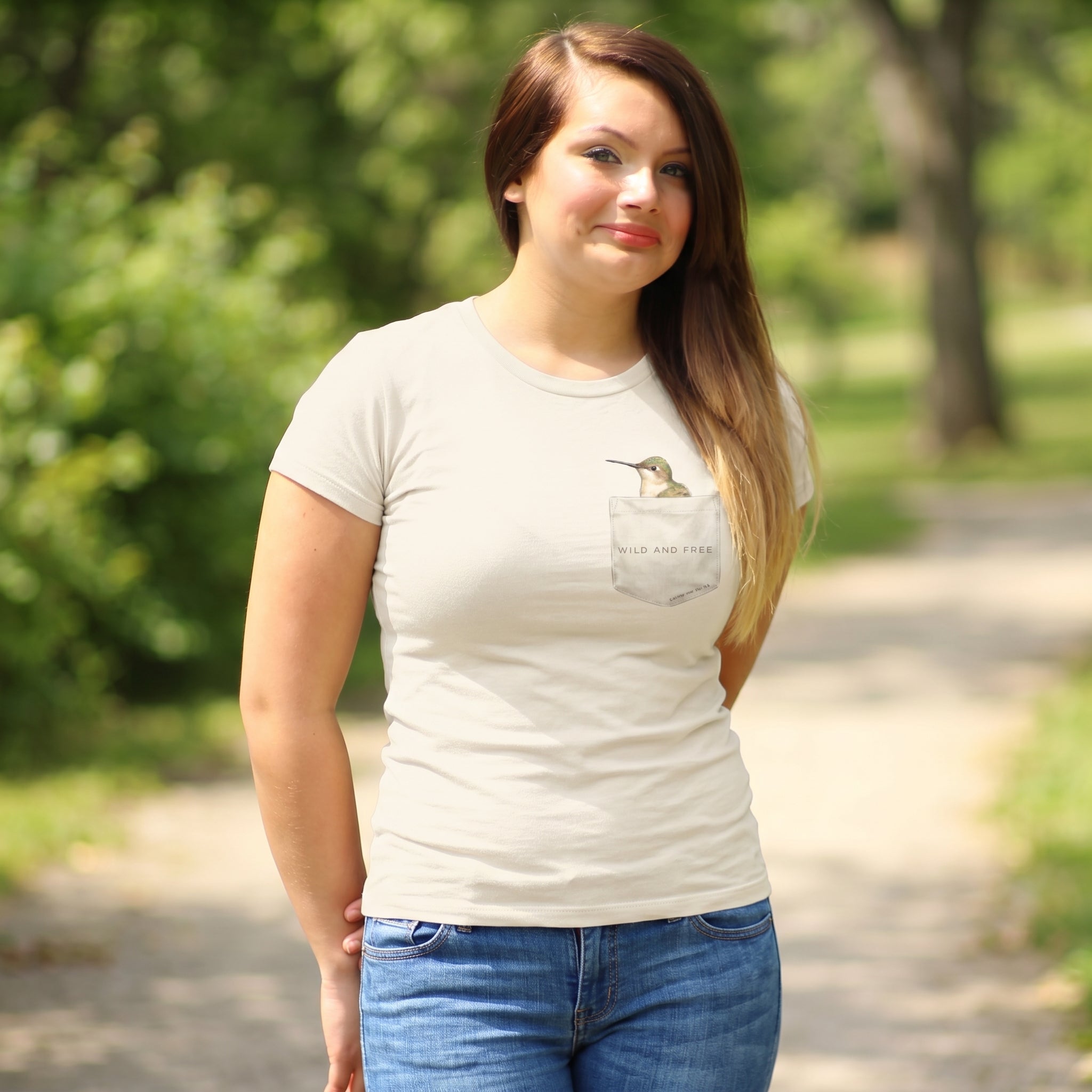 Woman wearing a beige t-shirt with a graphic design of a hummingbird and faux pocket