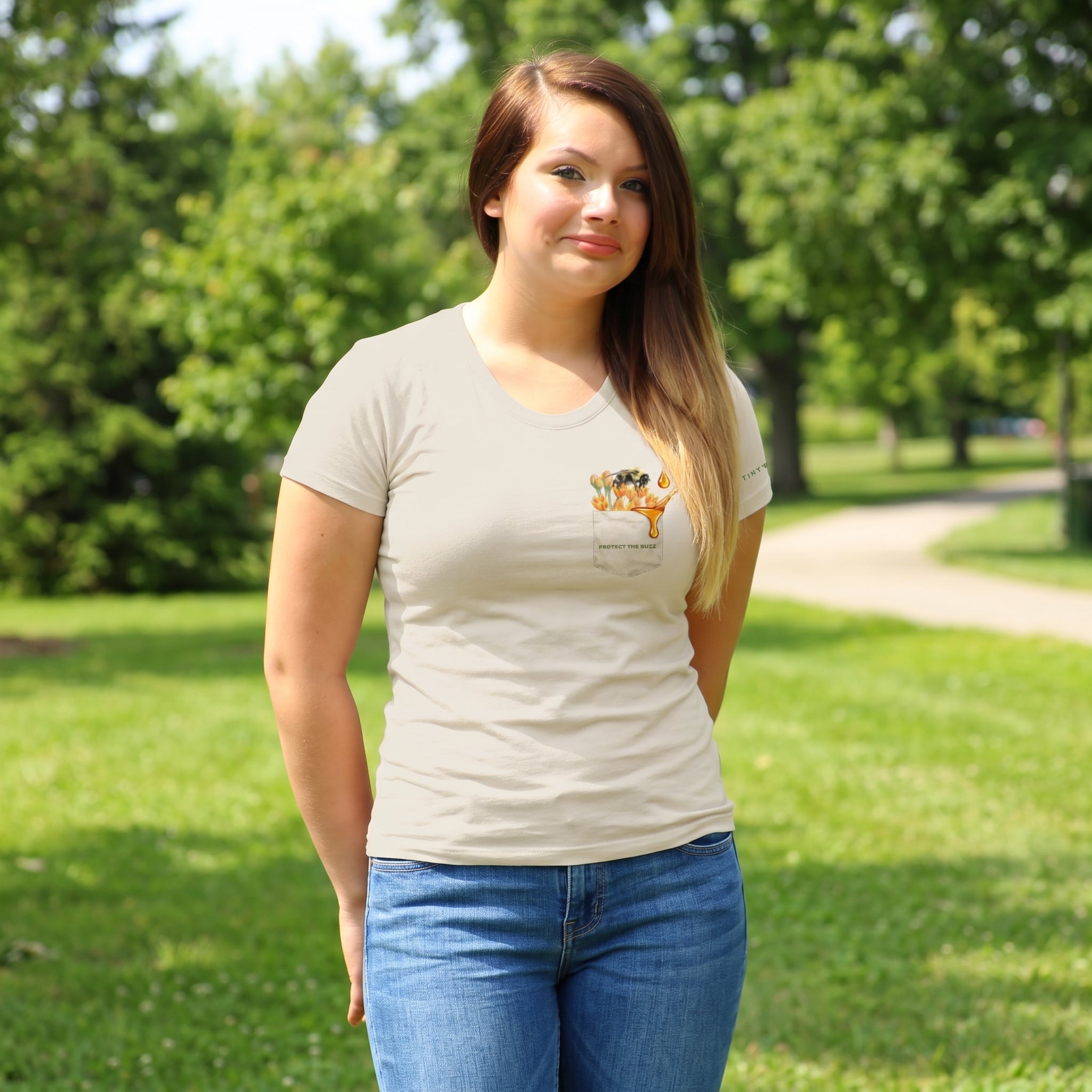 Woman wearing a beige t-shirt with a bee and flower design in a park