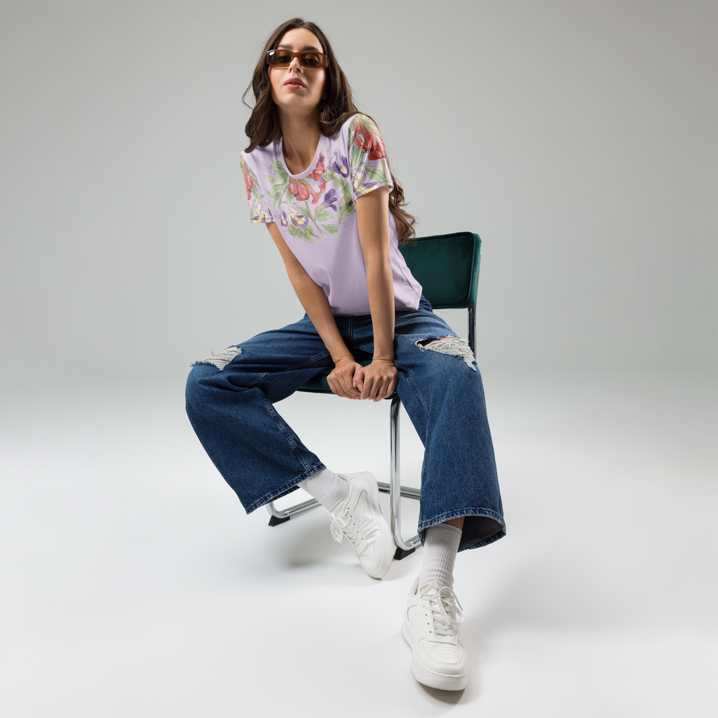 Woman sitting on a chair wearing a red and white floral shirt, blue jeans, and white sneakers.