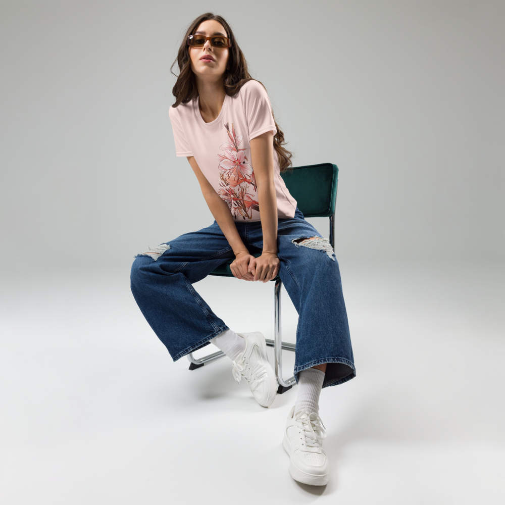 Person sitting on a chair wearing a peach T-shirt with floral design, blue jeans, and white sneakers.
