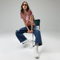 Woman sitting on a chair wearing a floral t-shirt, blue jeans, and white sneakers.