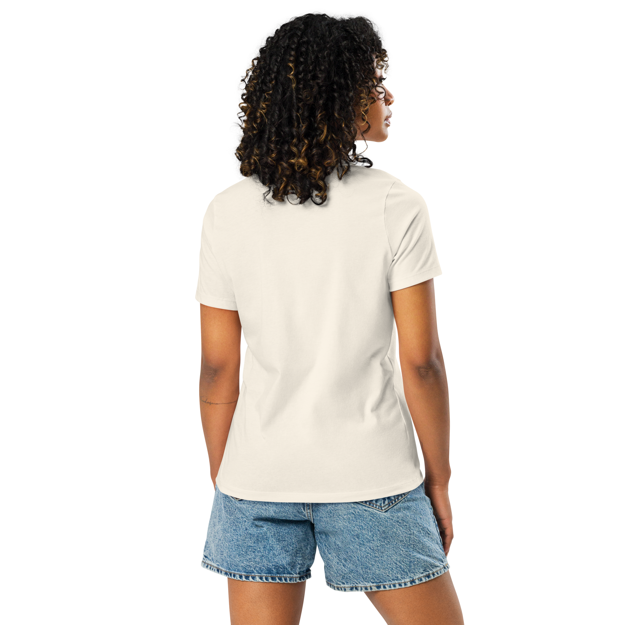 back view of Woman wearing a beige t-shirt with bee and flower and text,  "BLOOM AND BUZZ"