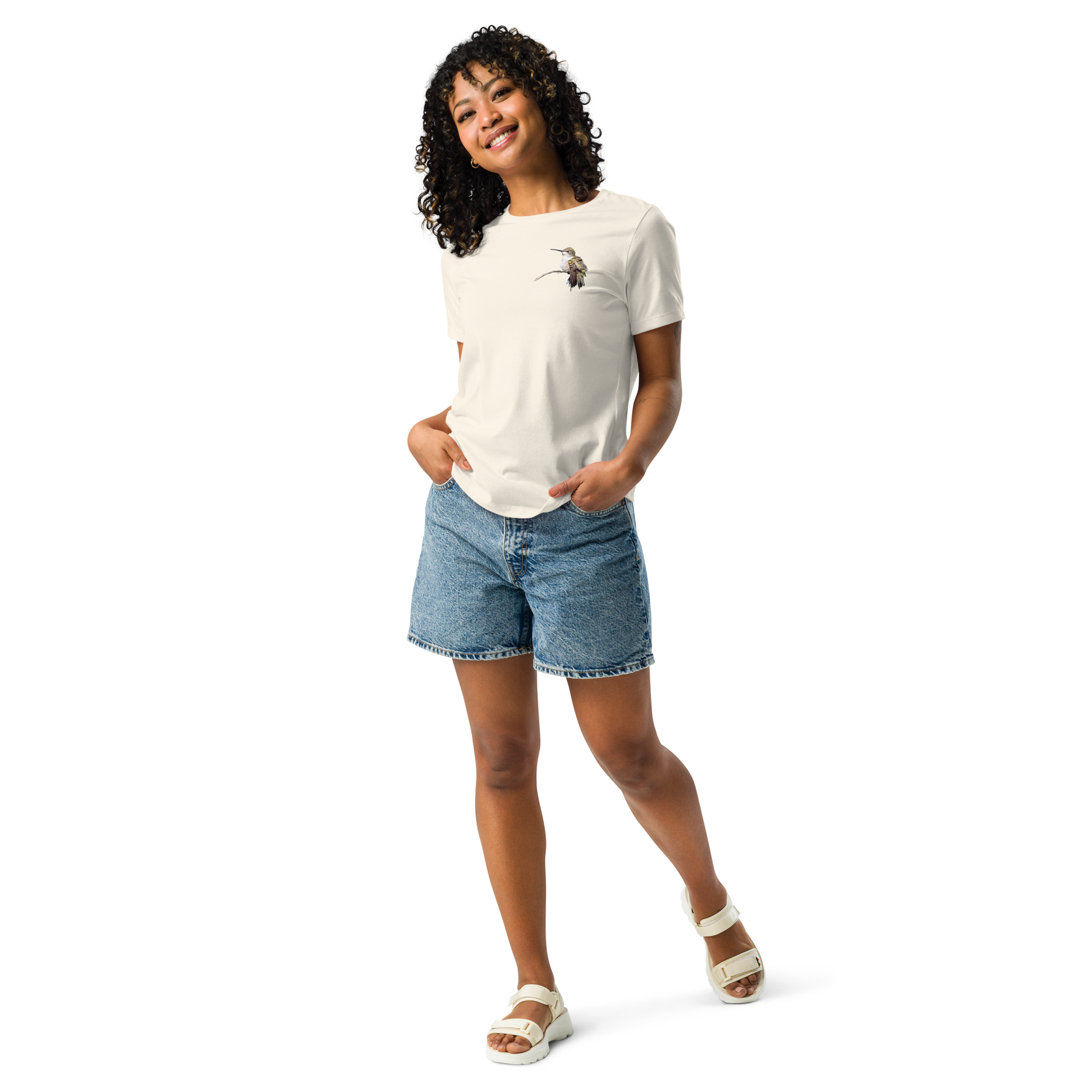 Woman wearing natural color tee shirt with photo of a hummingbird on a branch and jean shorts