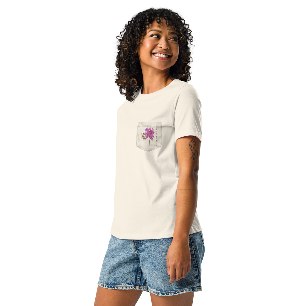 Woman wearing a beige t-shirt with bee and flower and text,  "BLOOM AND BUZZ"