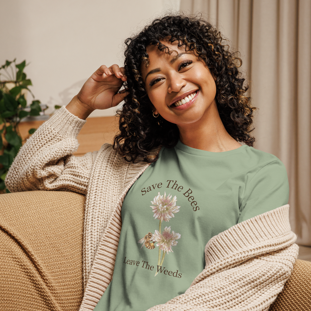 Woman wearing a sage t-shirt with text Save The Bees and graphics, sitting on a couch.